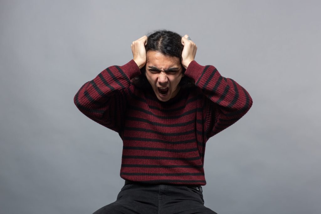 Guy shows anger while holding his head